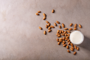 Almond milk served with almonds over brown texture background. Top view, flat lay. 